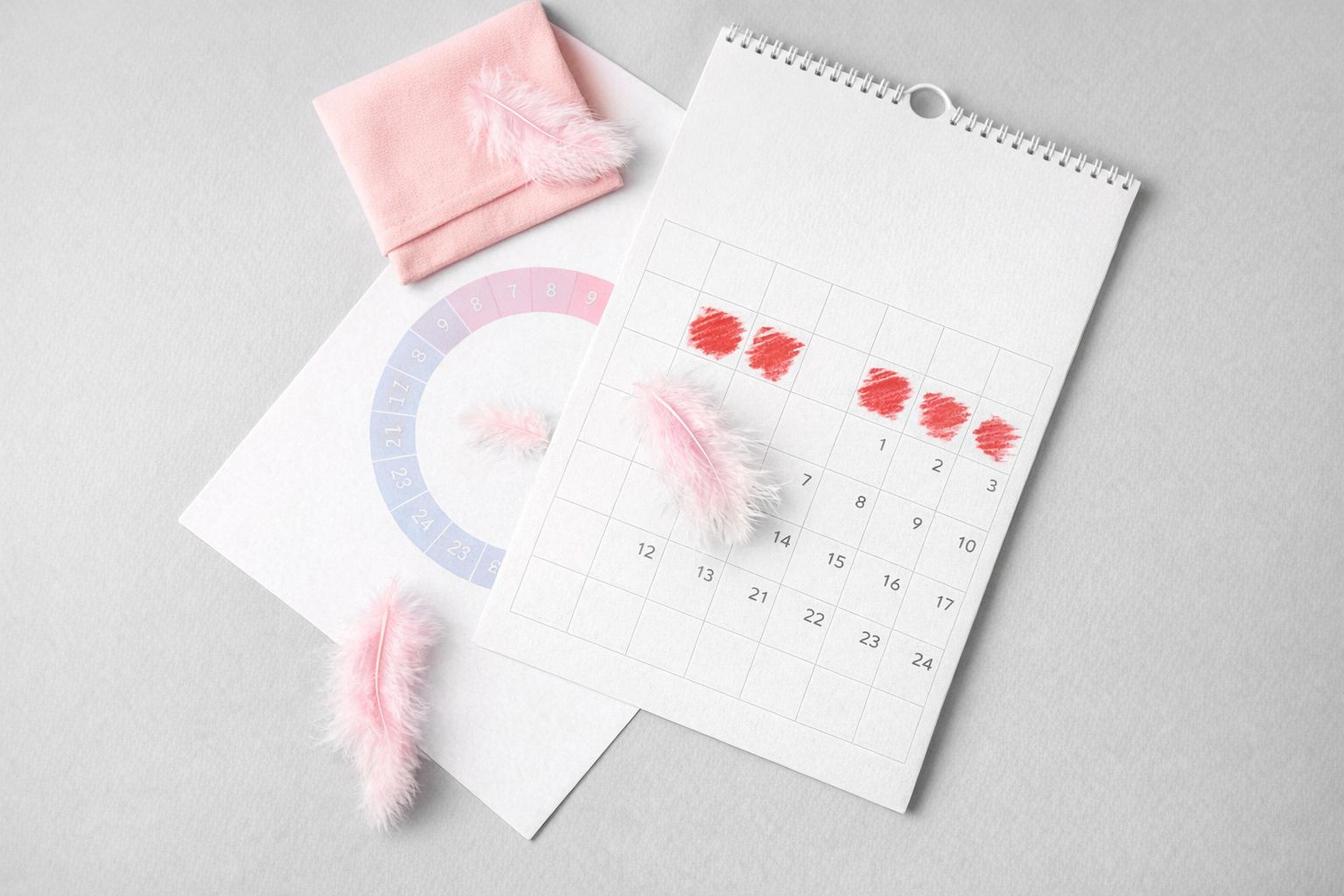 Menstruationskalender med rosa fjädrar och markerade datum för cykelplanering.