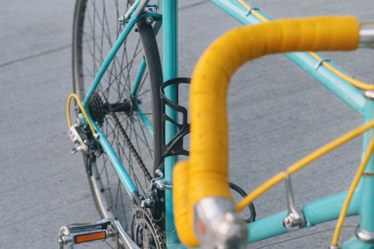 Närbild på en turkos racercykel med gul styrlinda och flaskhållare.